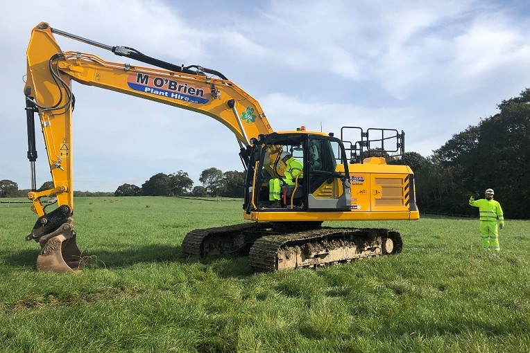 An image showing a yellow digger on grassland at the Sisk site.